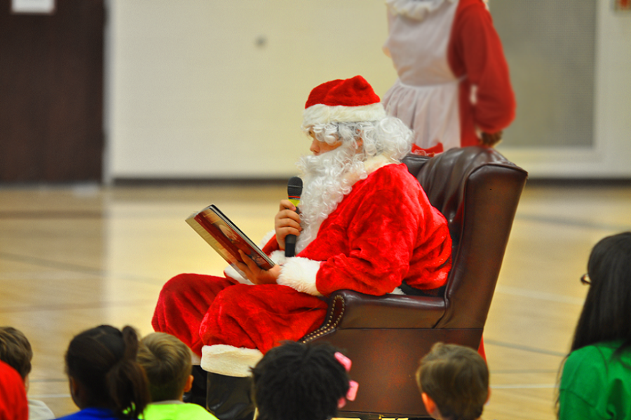 A crowd of children watch as some of their friends are chosen to sit at Santas feet