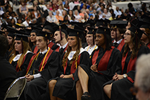 The front row of graduates sit patiently as the other members of the class go on stage. 