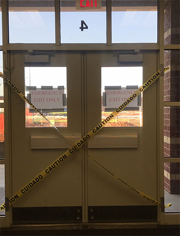 Caution tape hangs on the doors between the high school and S9, reminding students that they must take the new crosswalk in order to cross the street. 