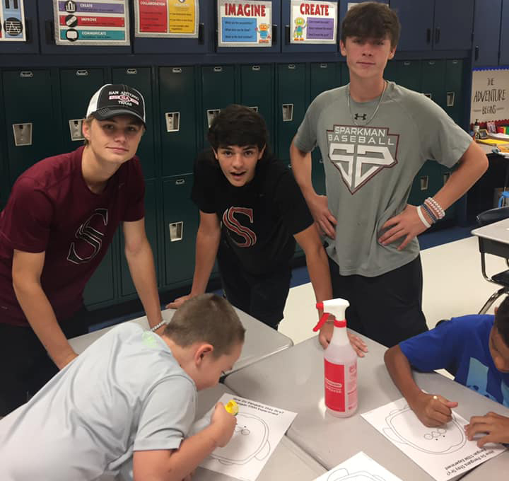 Baseball players Brendan Vatz, Cooper Posey and Tucker Burns help Legacy students draw a picture after reading them a book. 