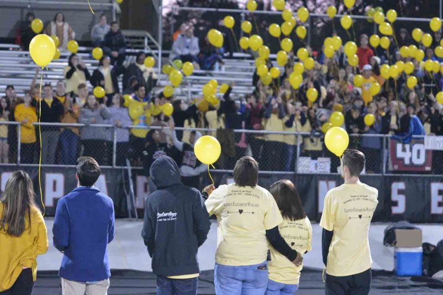 Members of the senior class stand on the football field before the Decatur kickoff to release balloons in honor of senior Lauren Wallace. Wallace lost her life in a car accident over fall break. 