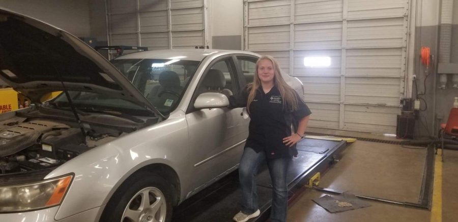 Posing by a car she worked on at Calhoun Community College, junior Kealey Weaver takes a break. Weaver takes a class at the local college to learn more about automotive mechanics. 