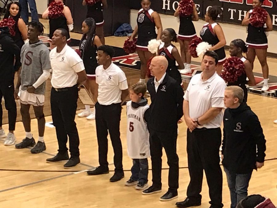 Monrovia Elementary student, Trey Hall, stands next to coach Jamie Coggins during the National Anthem. 