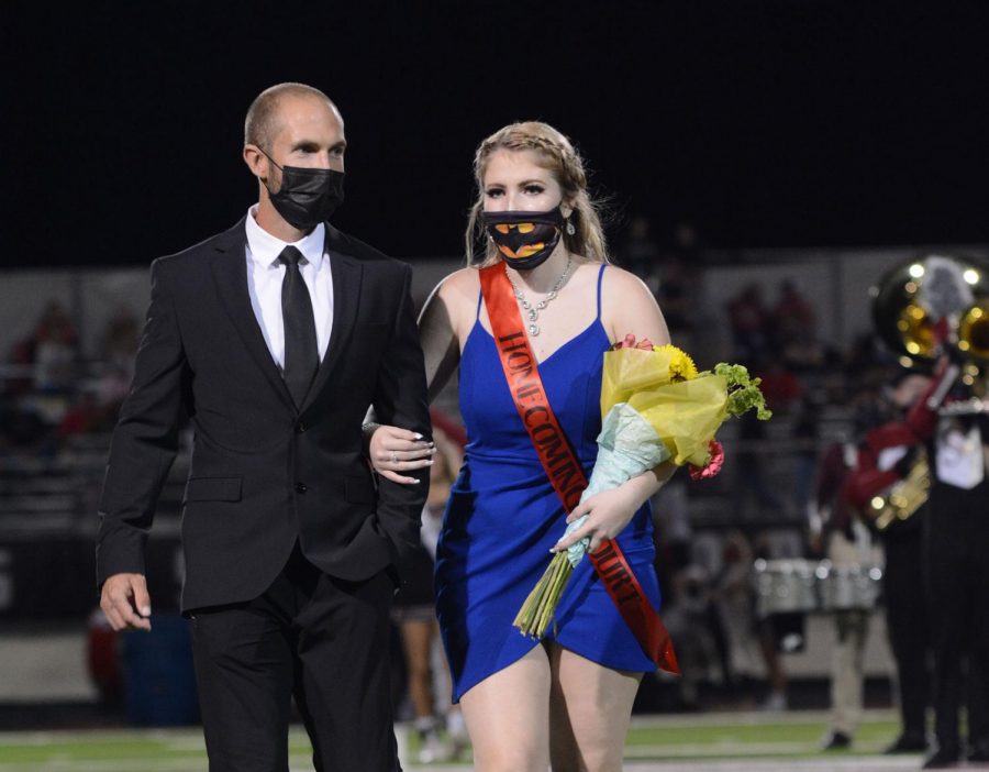 Junior Azlyn Miller walks across the field with her father during the Sept. 8 homecoming. Due to COVID, homecoming was conducted without students being in session. 