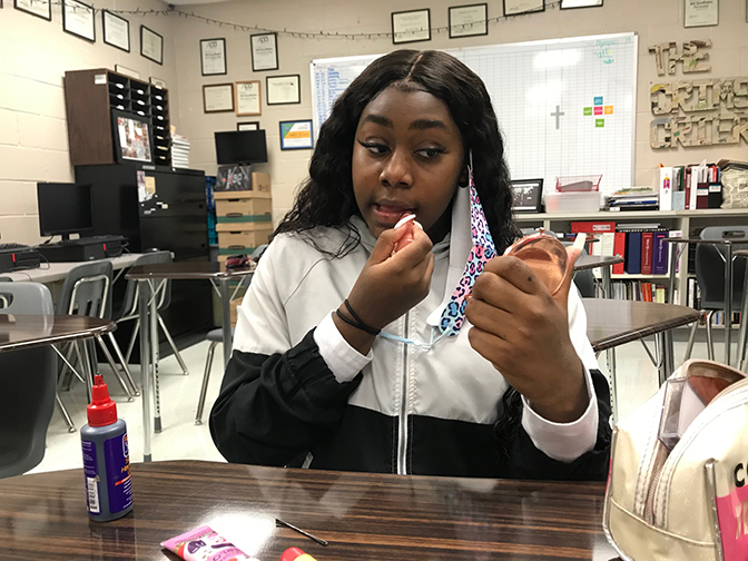 Senior Cherish Hollie tests one of her lip gloss products in first period. She shared how the gloss shines with her classmates. 