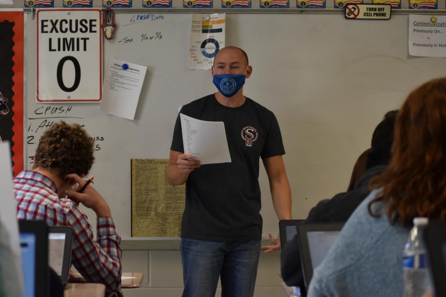 History teacher, Mr. Bret Larsen, discusses papers with his students. 