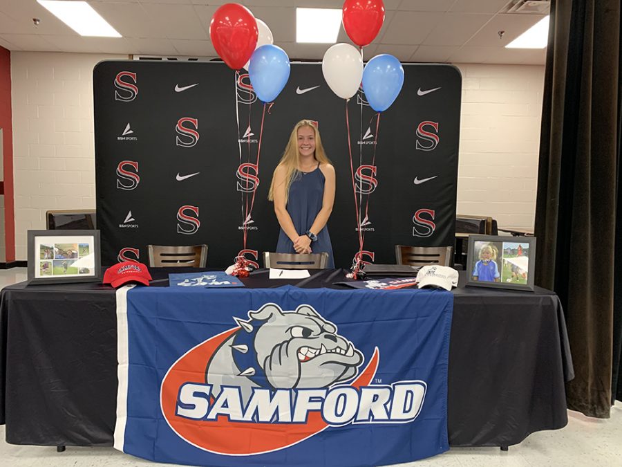 Before greeting her family and friends, senior Kellie Hovis poses for a quick photo to begin her signing ceremony. 