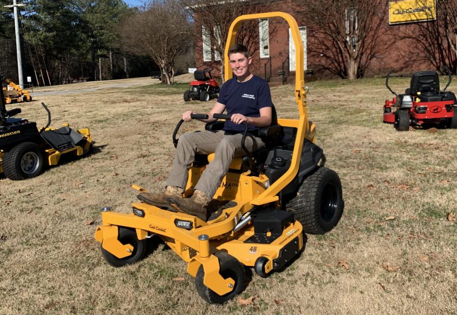 Controlling the lawnmower, senior Alden Hall works on completing his work. 