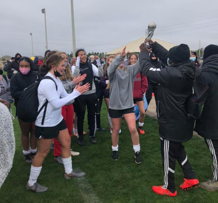 The girls soccer team accepts a trophy from the first tournament of the season.