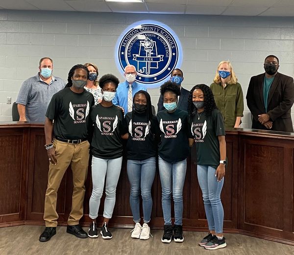 The girls 4x100 relay team and coach Cedric Austin receive recognition at the May board meeting. 