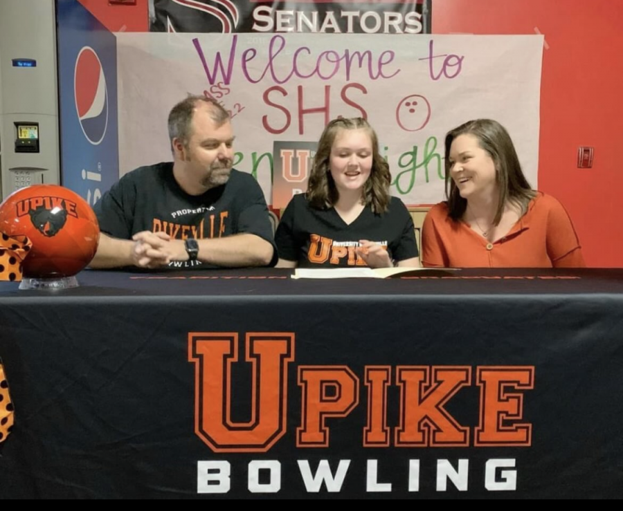 Senior Emily Lindsey signs her scholarship with her parents present at her signing party held on Dec. 9.