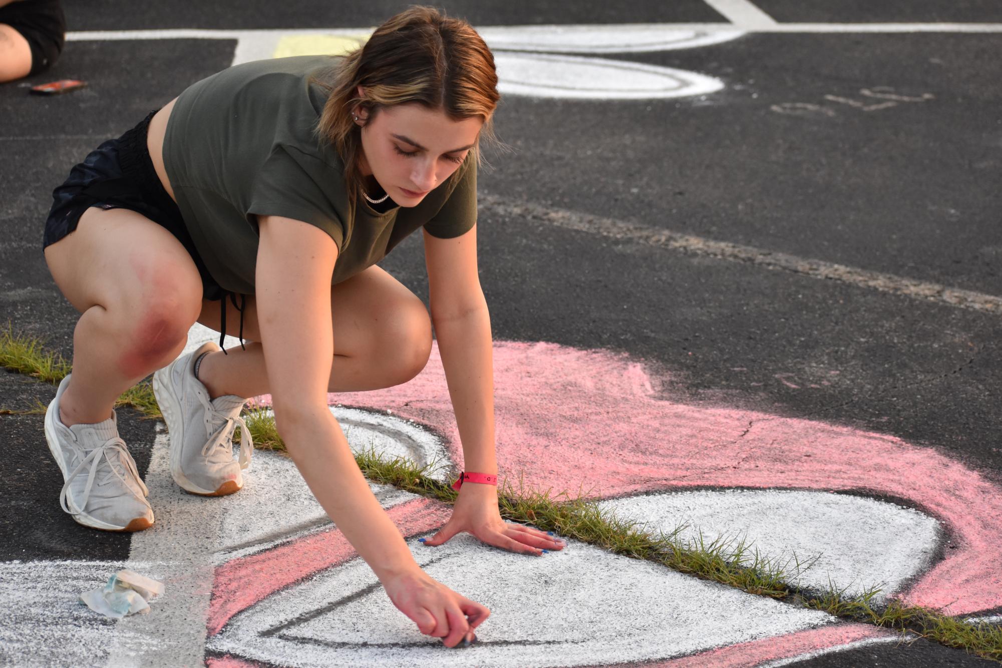 Senior Camryn Combs fills in a circle with white chalk. Combs was one of 100 students who participated.